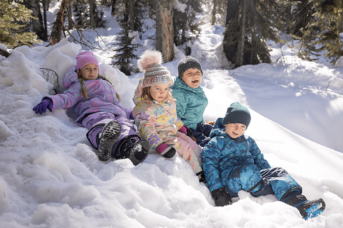 Kids sitting on a snowy hill in Therm Kids waterproof clothing